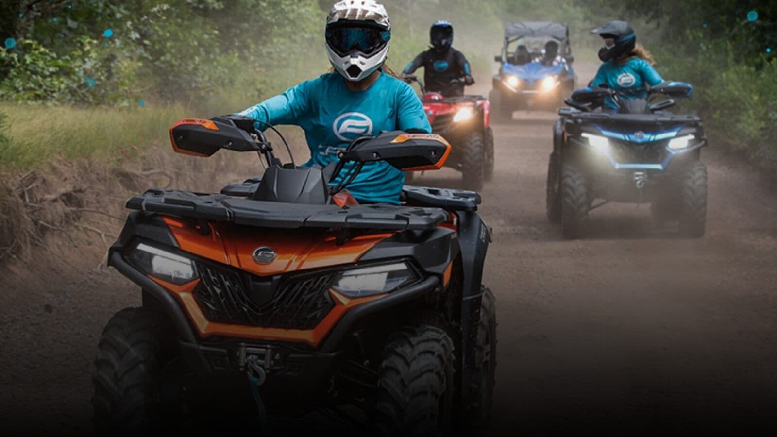 A group riding quad bikes along a dirt track