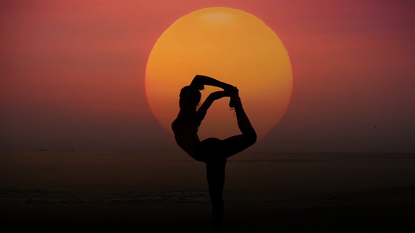 A yoga pose in silhouette against the setting sun