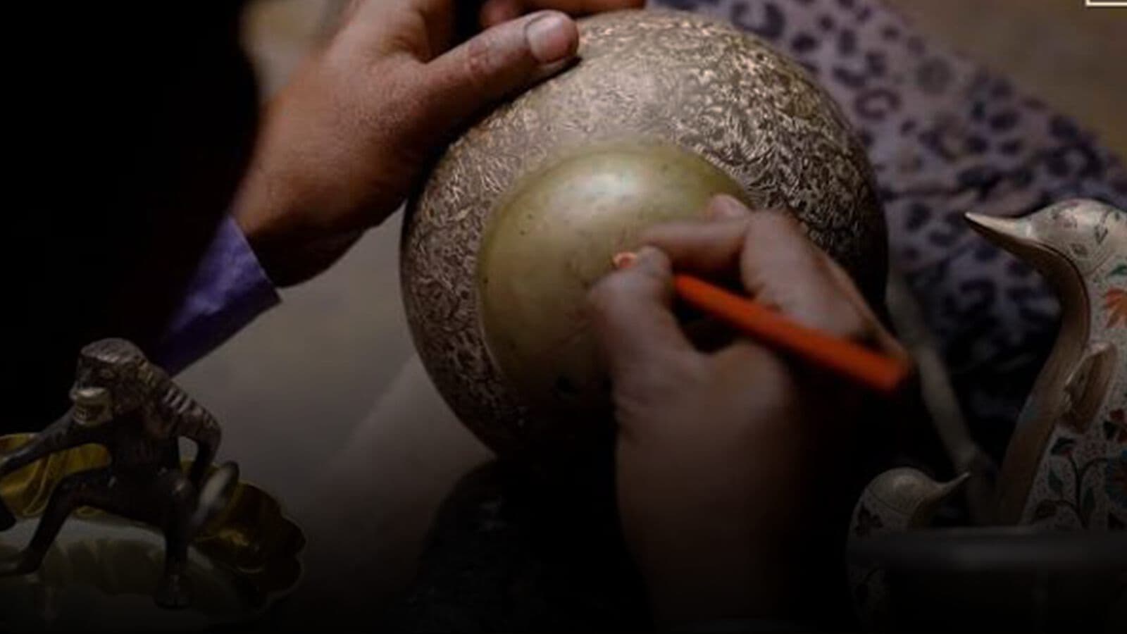 A craftsman engraving a brass vessel
