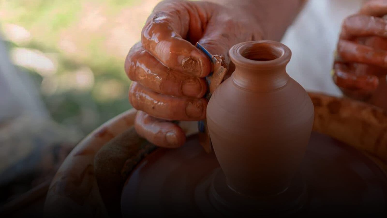 Hands shaping a pot on a wheel