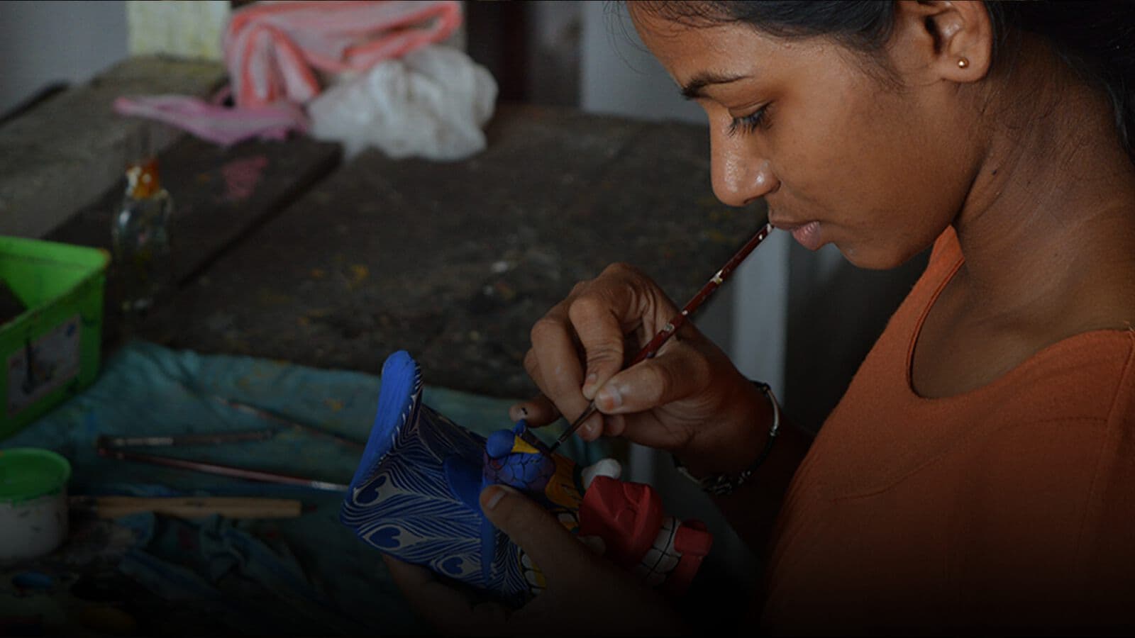 An artisan painting a carved mask