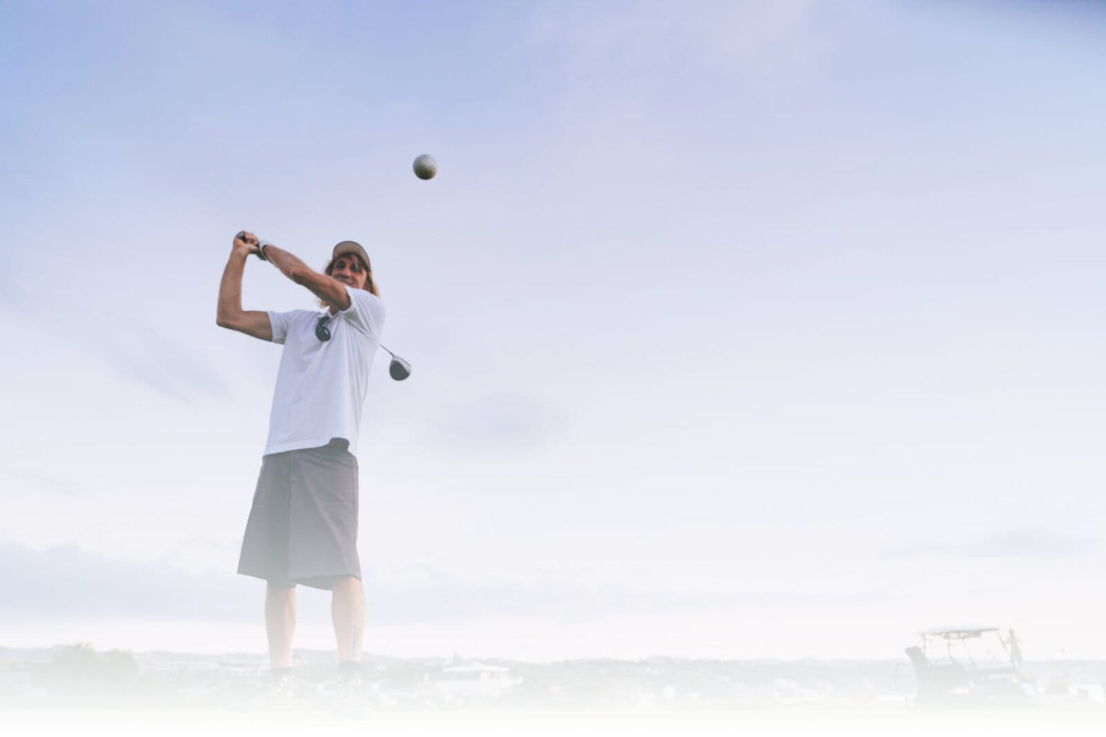 A golfer mid-swing against an open sky