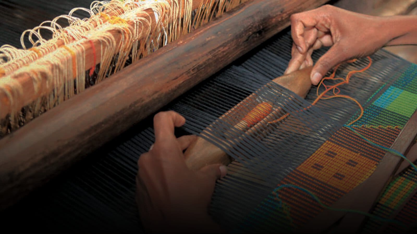Hands passing a shuttle across a handloom