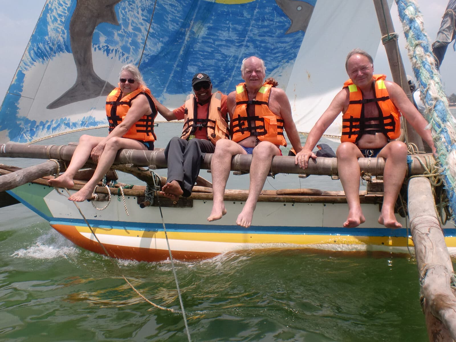 Sitting along the outrigger of a sailing boat in life jackets
