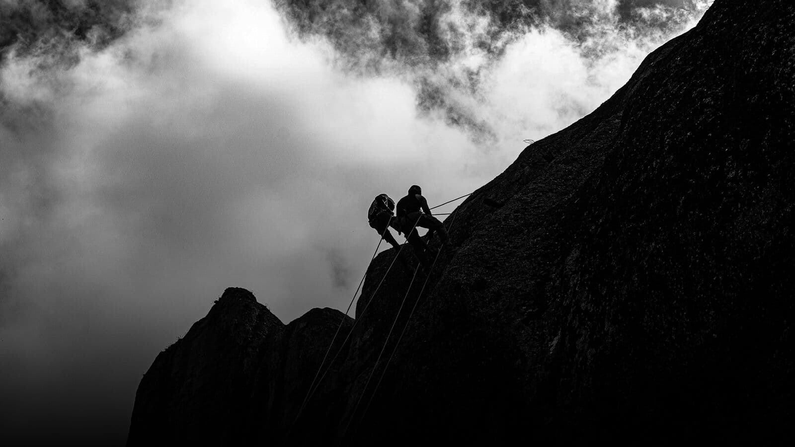 A climber rappelling down a wet rock face