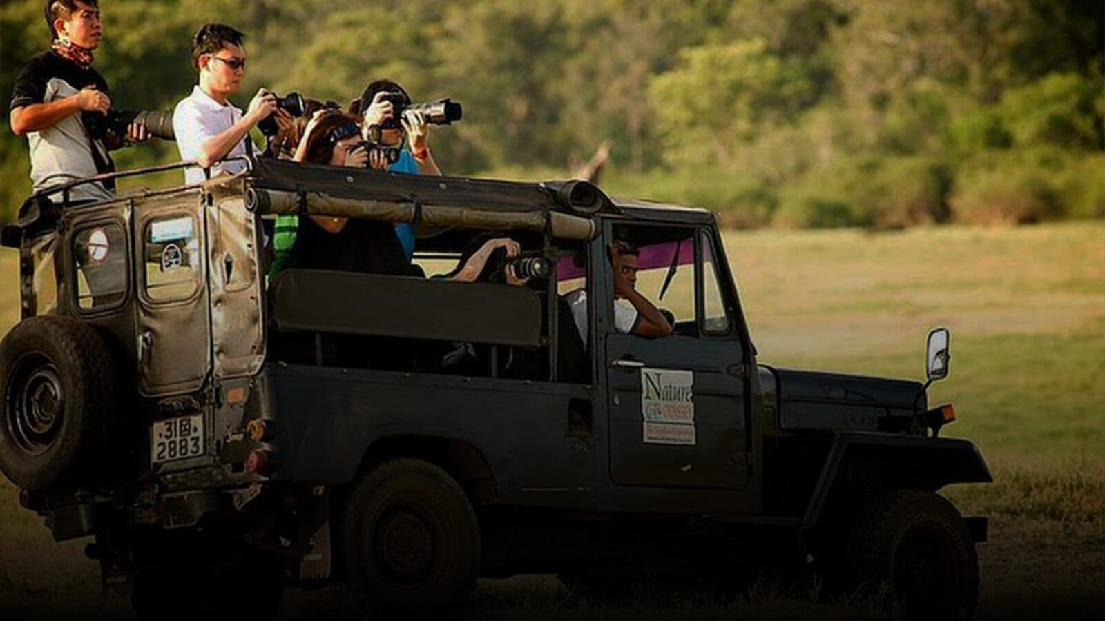 Travellers photographing from an open safari jeep