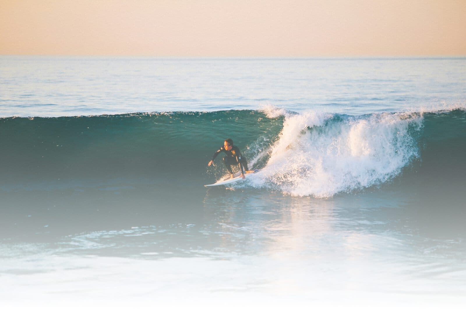 A surfer on a wave in evening light